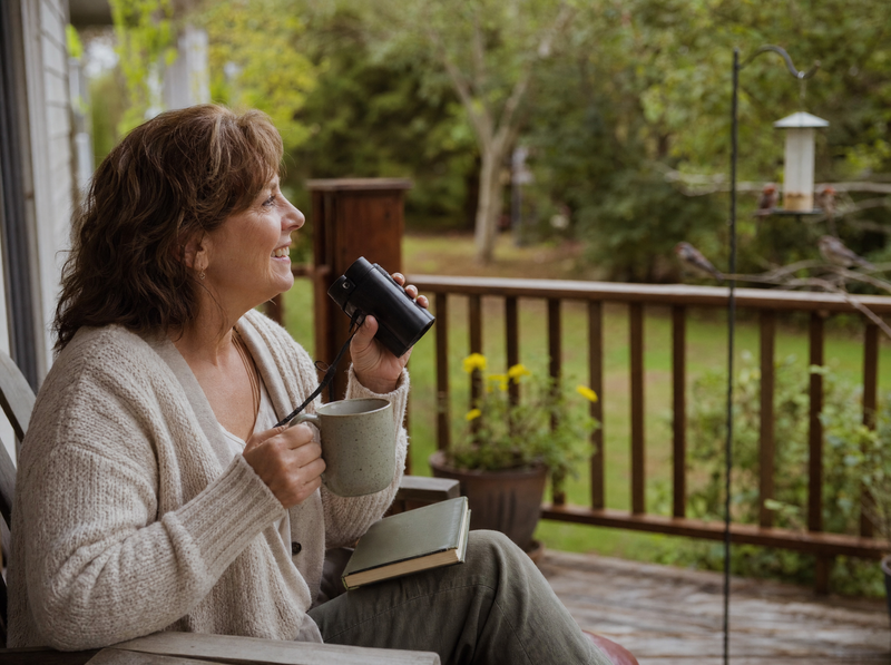Woman watching birds from her porch with a mug